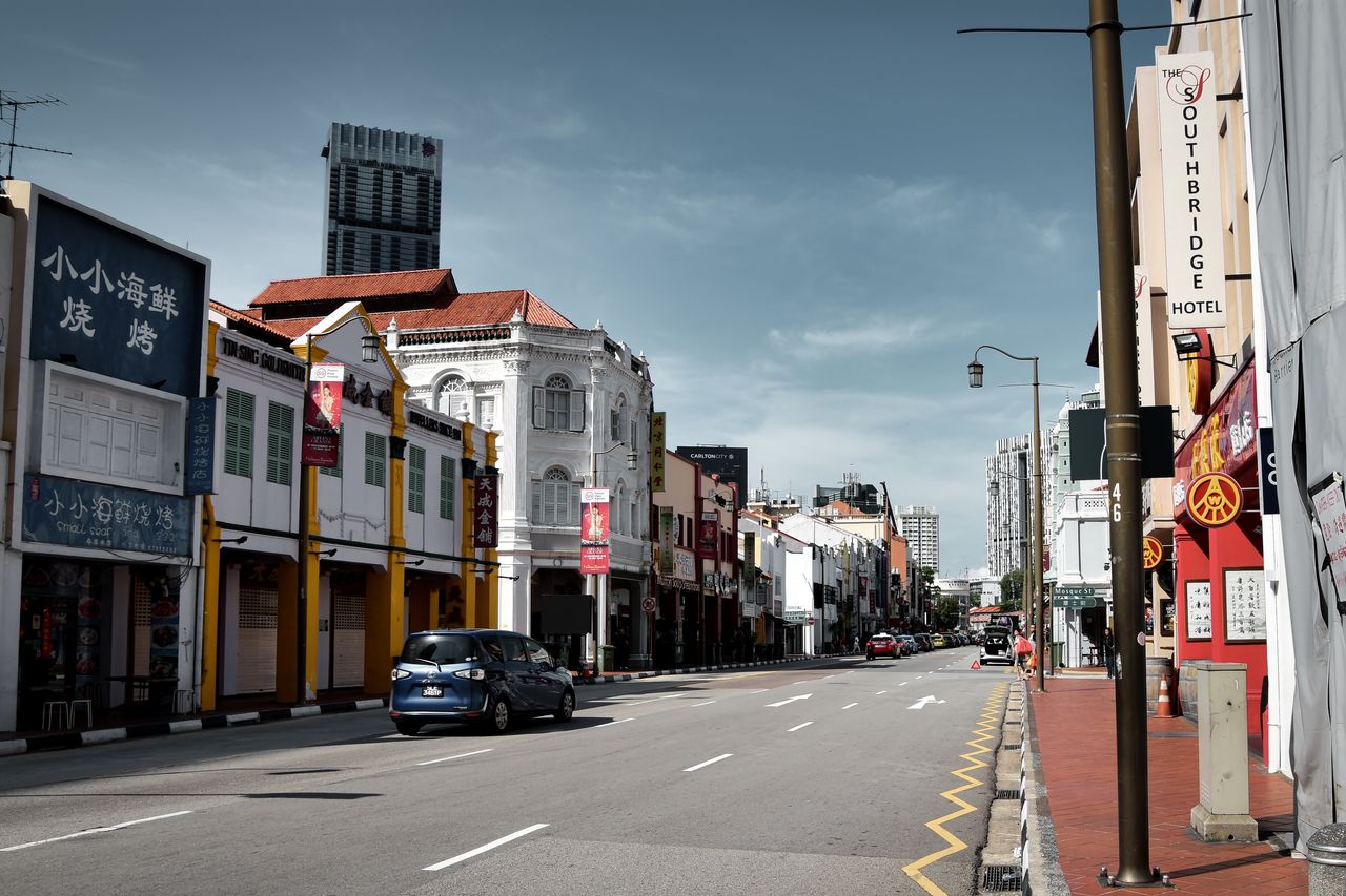 A vibrant street in Singapore lined with historic shophouses and modern buildings under clear skies.