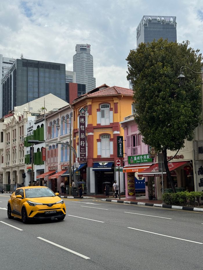 Colorful Chinatown street with modern skyscrapers in the background, featuring a striking yellow car.