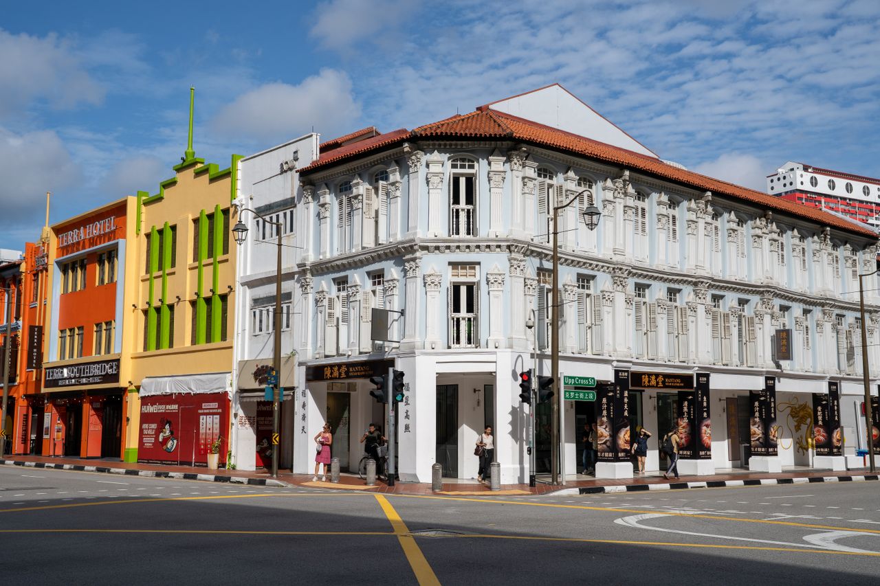 Vibrant colonial buildings in Chinatown with people on the street corner on a sunny day.